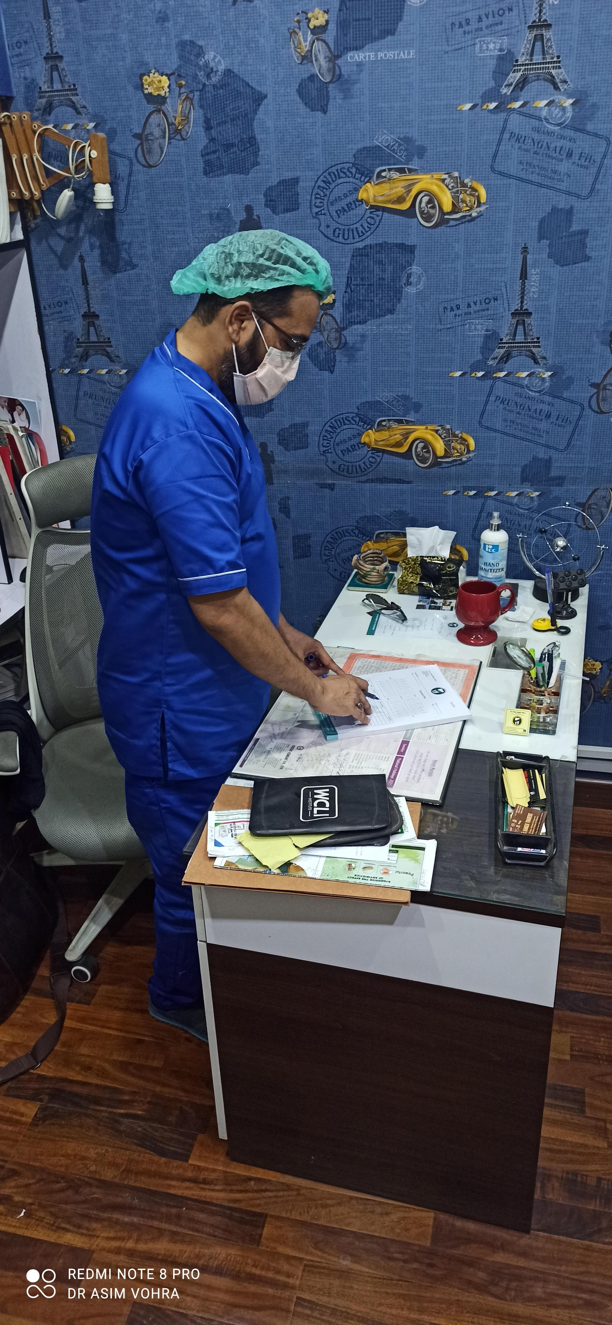 Dr. Asim Habib Vohra in scrubs reviewing patient notes at his desk